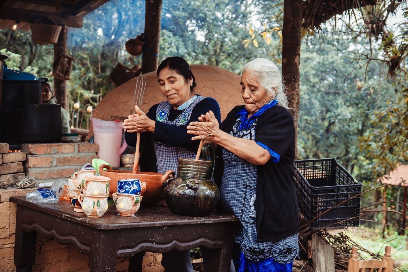 Senhoras mexendo uma panela de barro